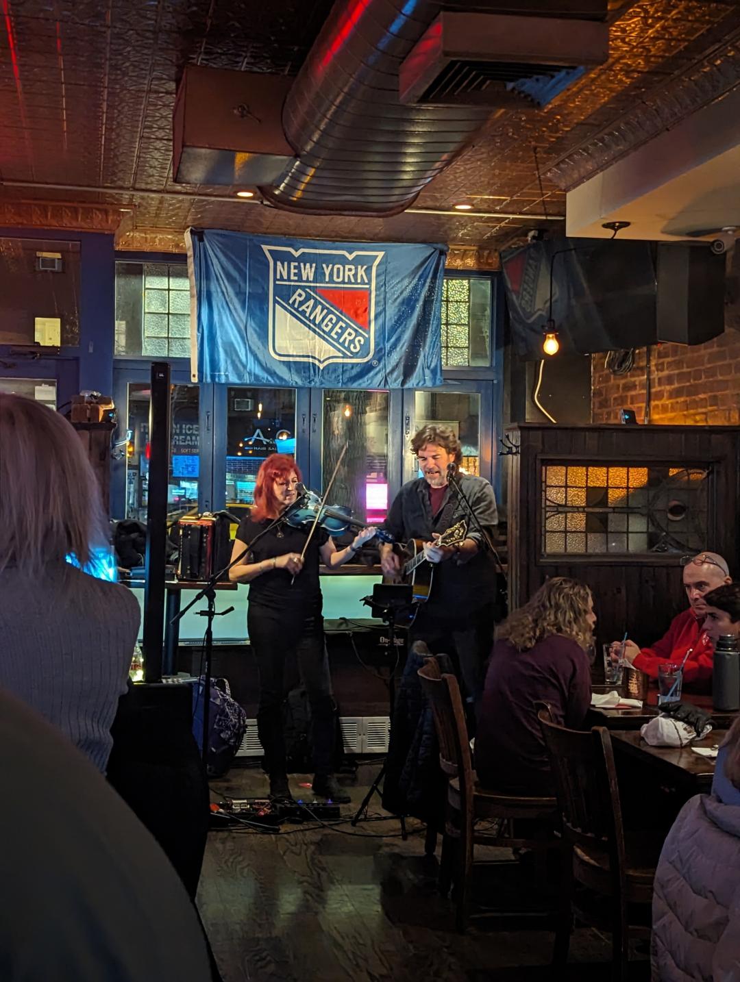 Deni Bonet playing a violin/fiddle and Chris Flynn playing a guitar in a local taven. 