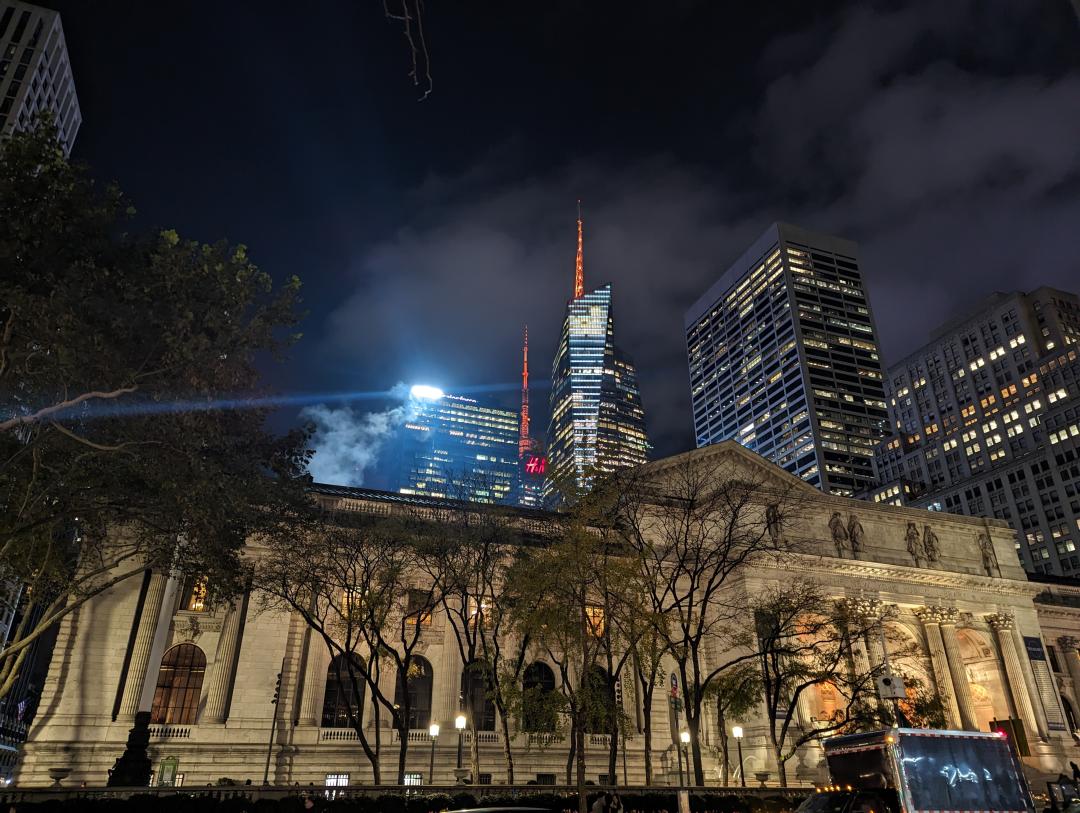 The NYC Public Library looking gothic and gloomy with neon lite skyscrapers in the background