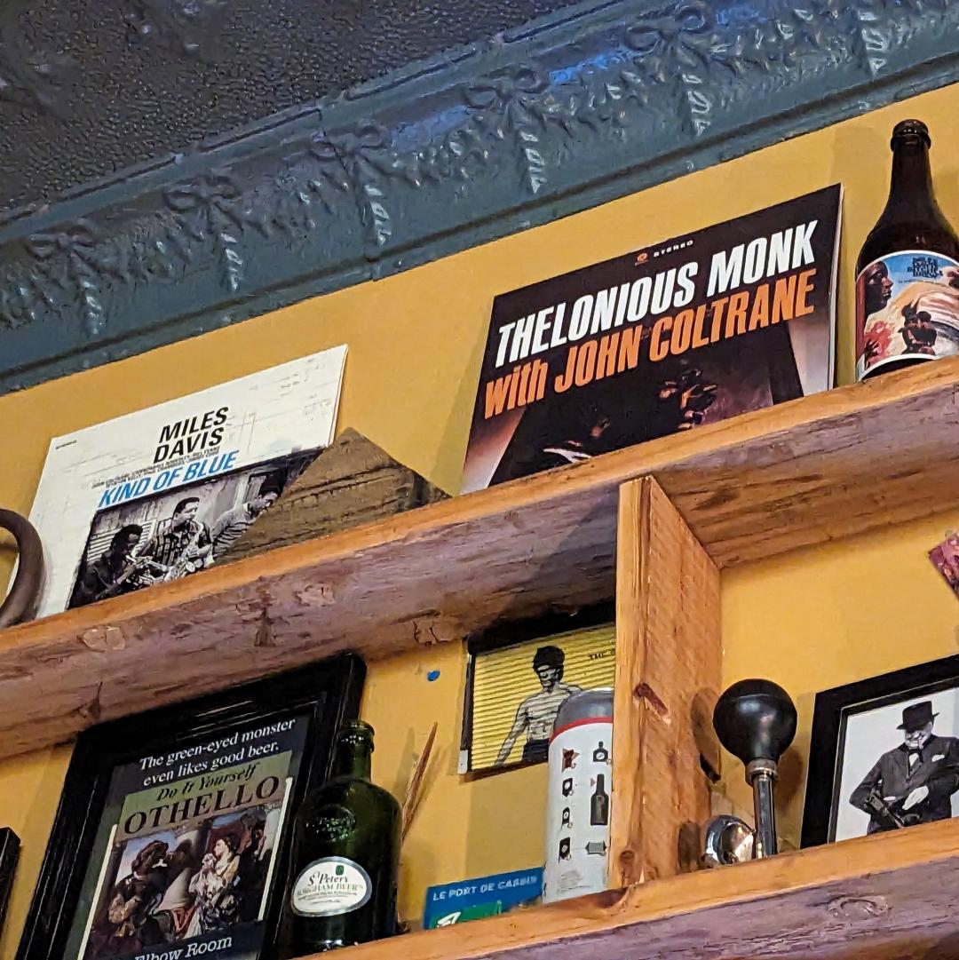 A photo of a high shelf in a bar with a Thelonios Monk with John Coltrane album on it. 