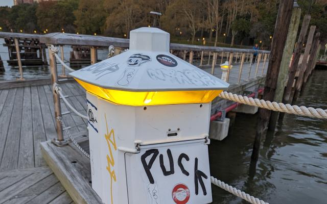 A unique lattern on a dock with graffati reading "Puck"