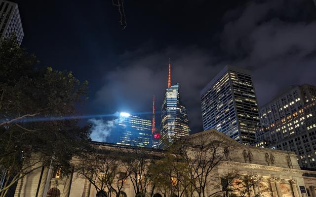 The NYC Public Library looking gothic and gloomy with neon lite skyscrapers in the background