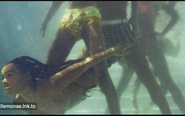 Album cover of the The Age of Pleasure byt Janelle Monae. Shows an underwater scene of a three men standing in a pool while a women swims underwater and between their legs.